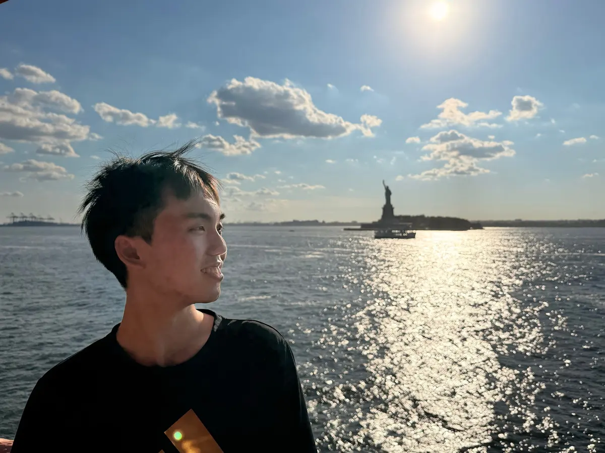 Alen Hsiao on the water in New York Harbor, the Statue of Liberty far behind.